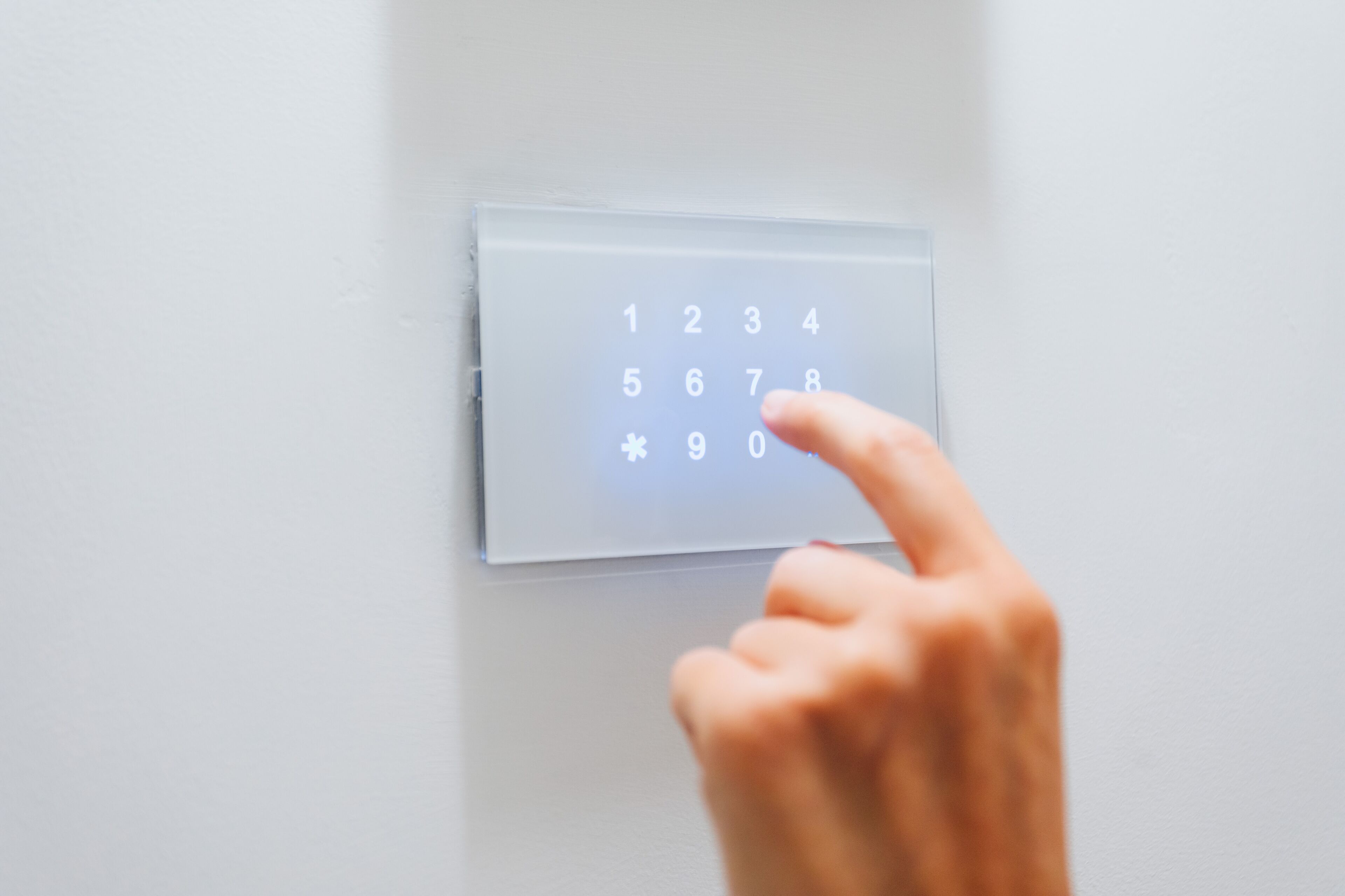 A hand pressing a numeric keypad on a wall-mounted device.