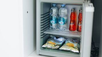 Mini-geladeira com garrafas de água, refrigerantes e embalagens de lanches.