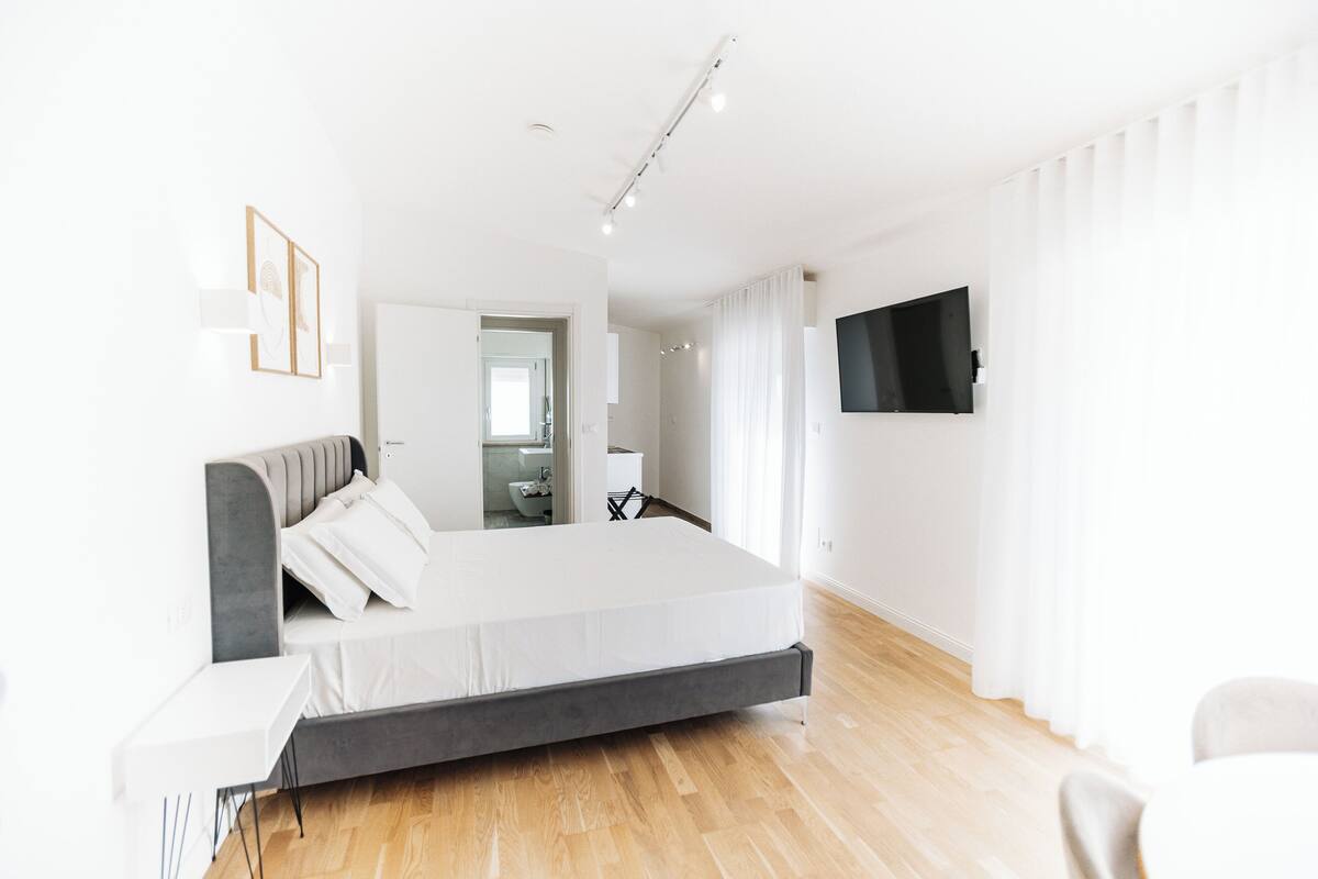 Un dormitorio moderno con una cama, mesita de noche y televisor montado en la pared.