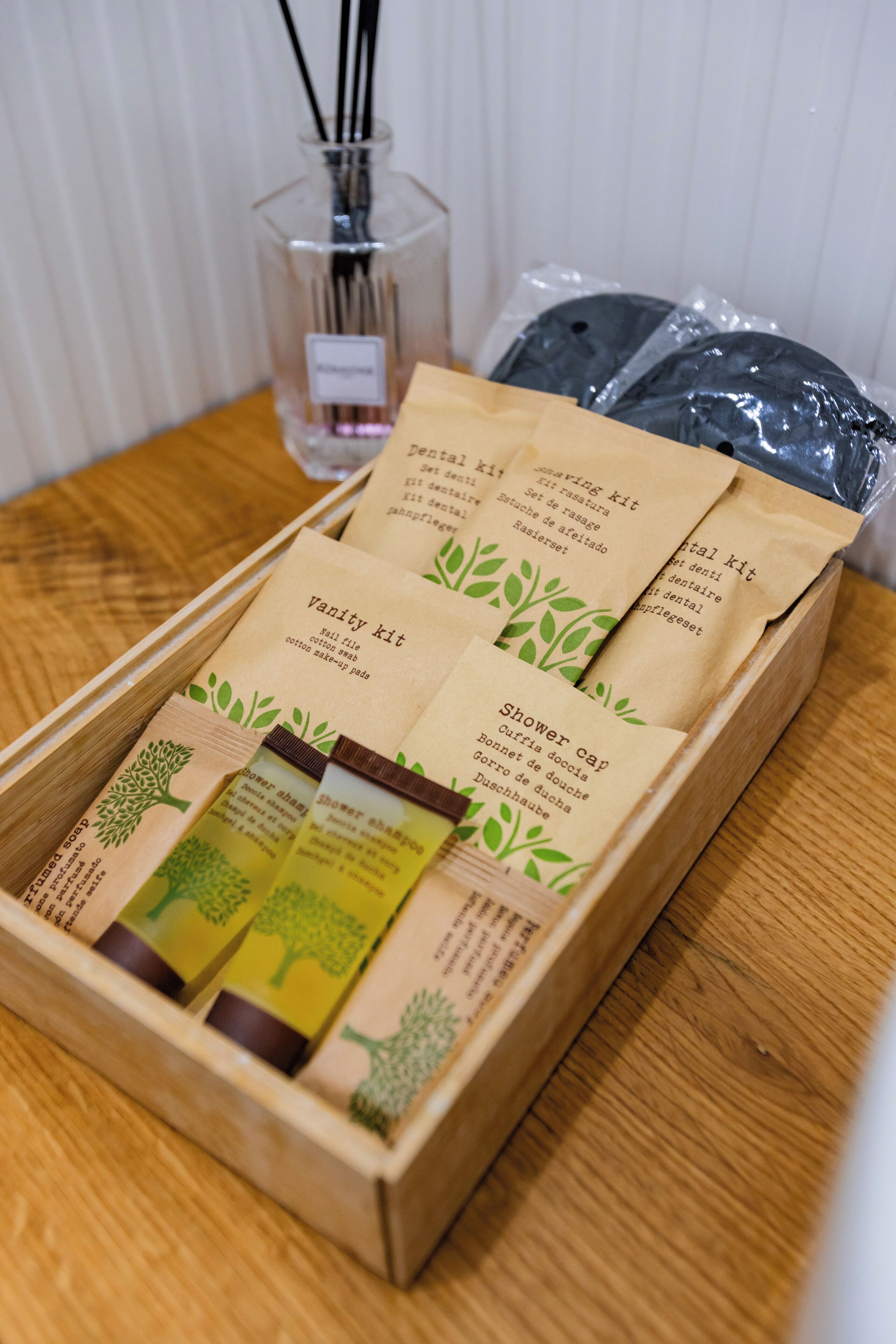 Una caja de madera que contiene un neceser, un organizador para la ducha y un juego de artículos de tocador.