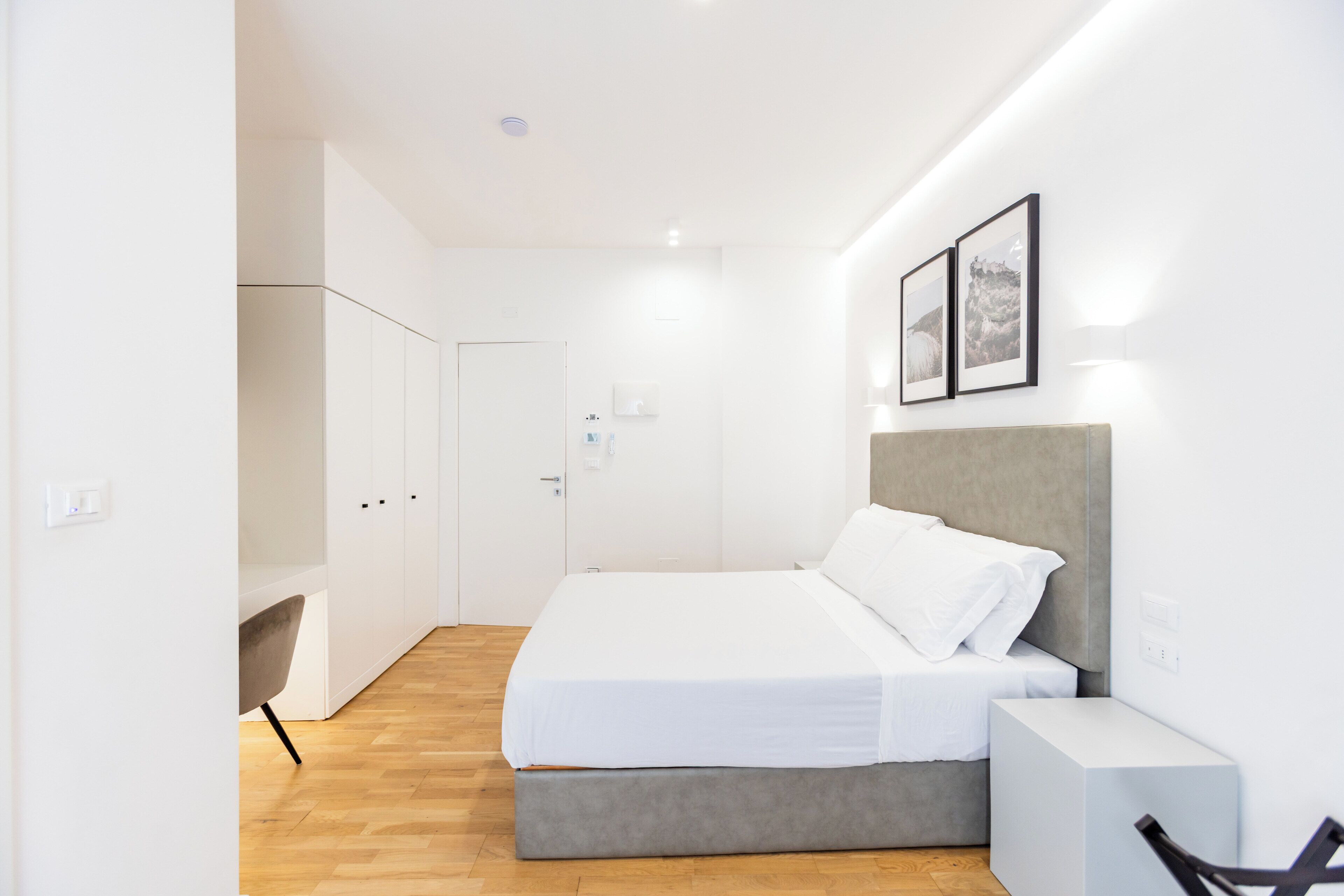 A modern bedroom with a bed, bedside table, and wardrobe.