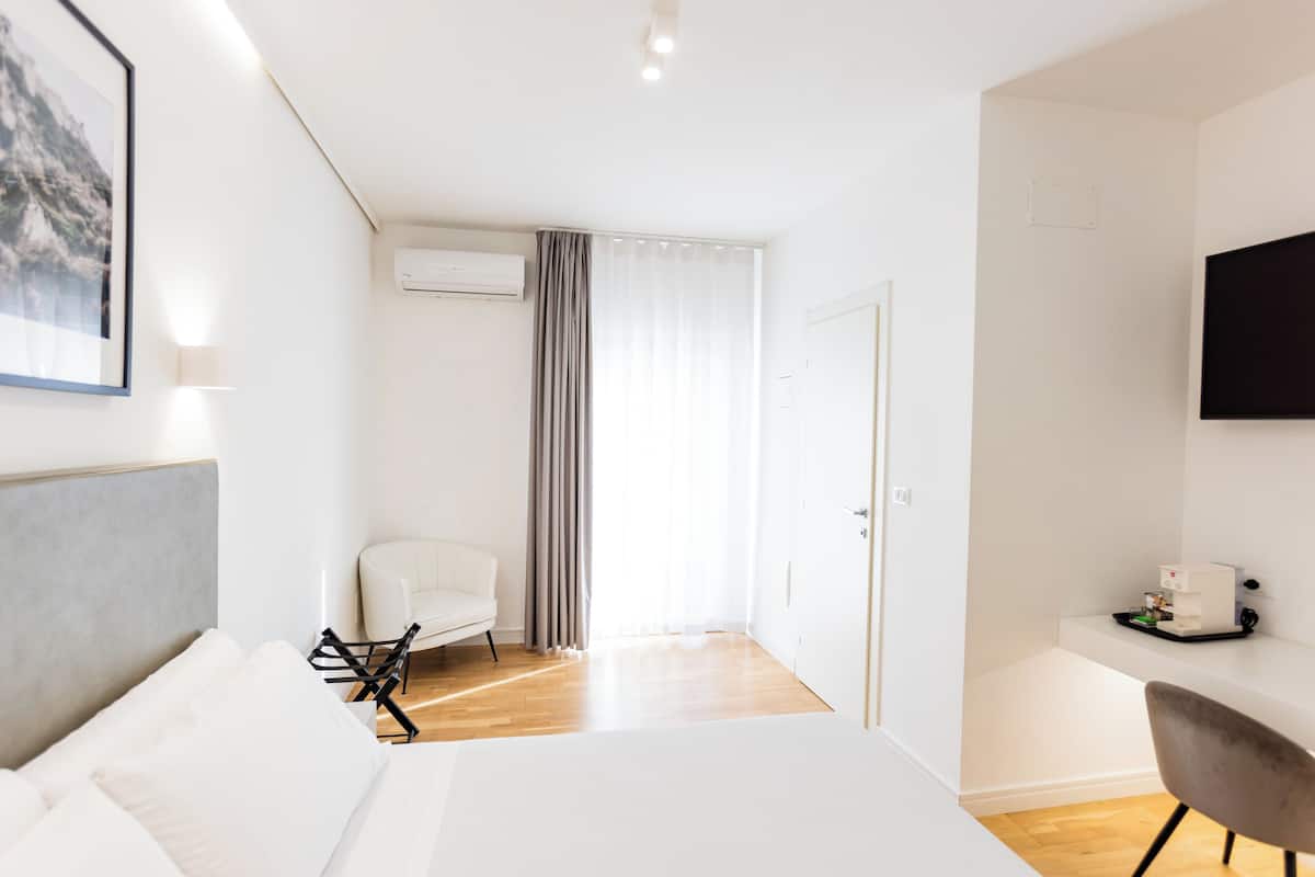 Una habitación de hotel moderna con cama, escritorio, silla y televisor.