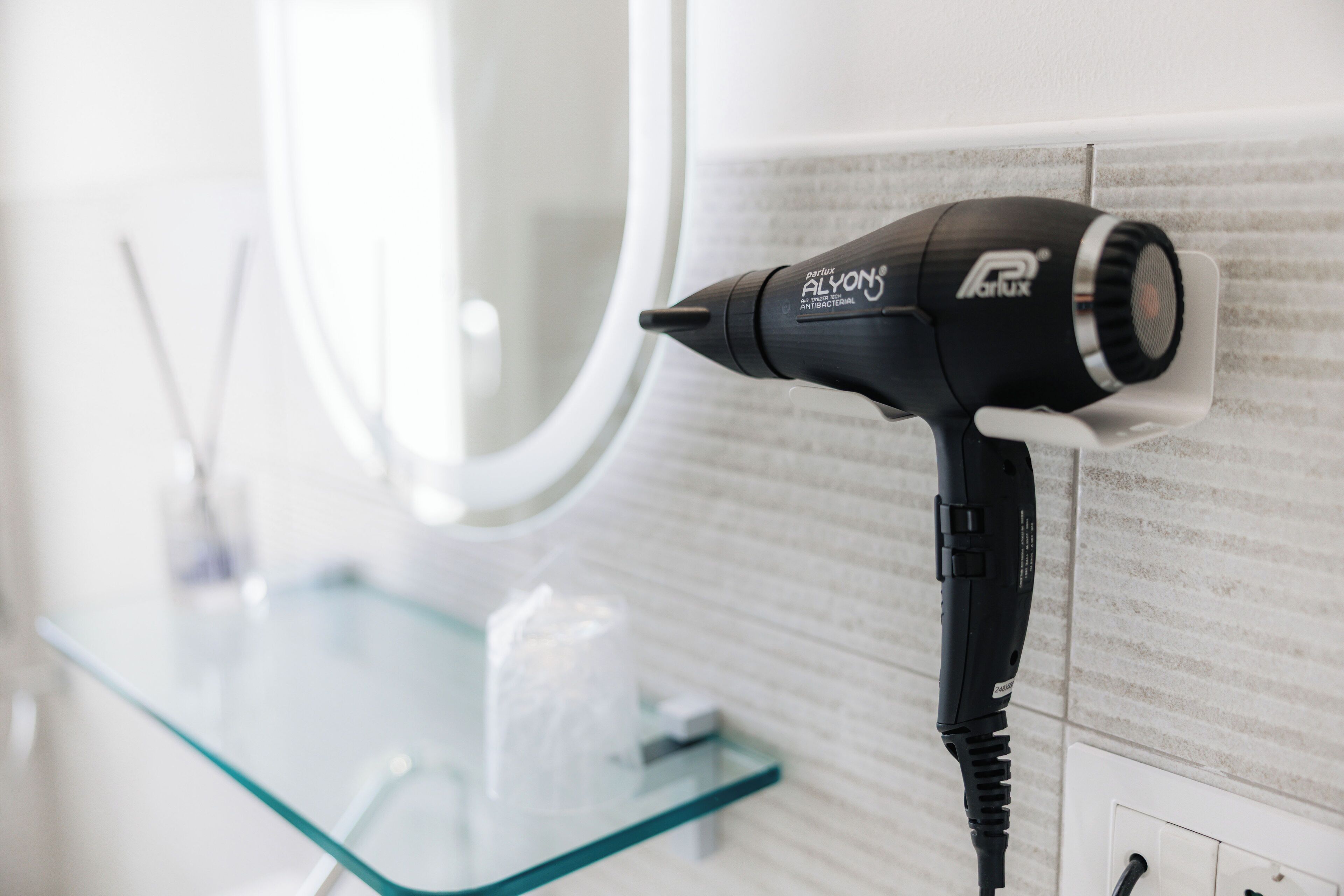 A hair dryer mounted on a tiled wall in a bathroom.