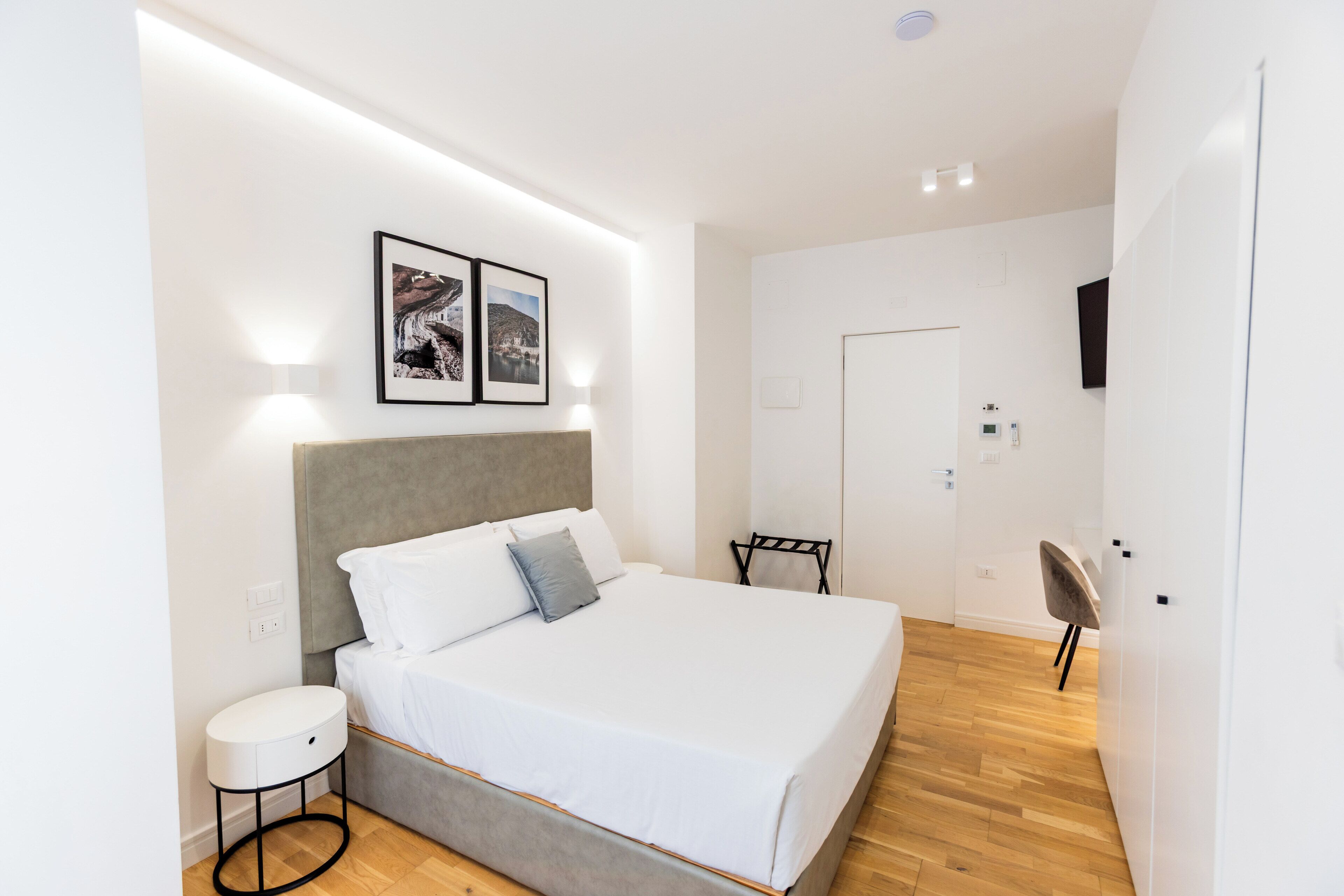 A modern bedroom with a large bed, a bedside table, and a wall-mounted TV.