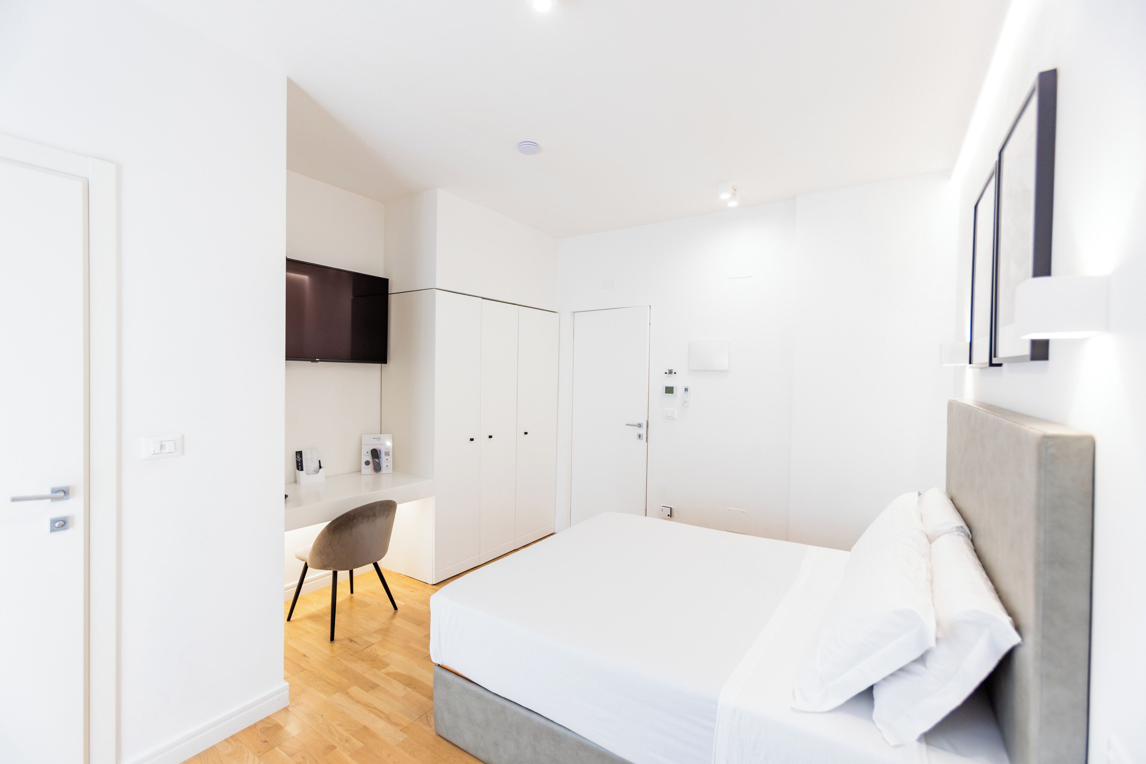 A modern bedroom with a large bed, a desk, and a chair.