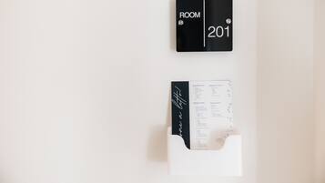Un letrero negro con la inscripción 'ROOM 201' y una carpeta blanca con anotaciones escritas a mano.