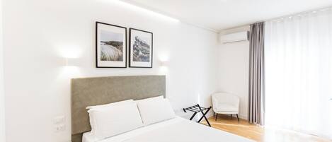 Une chambre d’hôtel moderne avec un grand lit, une chaise et deux tableaux encadrés au mur.