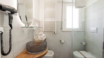 Un baño moderno con cabina de ducha de vidrio, tocador de madera y un inodoro con toallero.