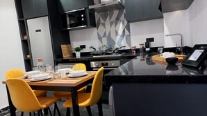 Ett modernt kök med en köksö i mitten, svarta skåp och gula stolar.