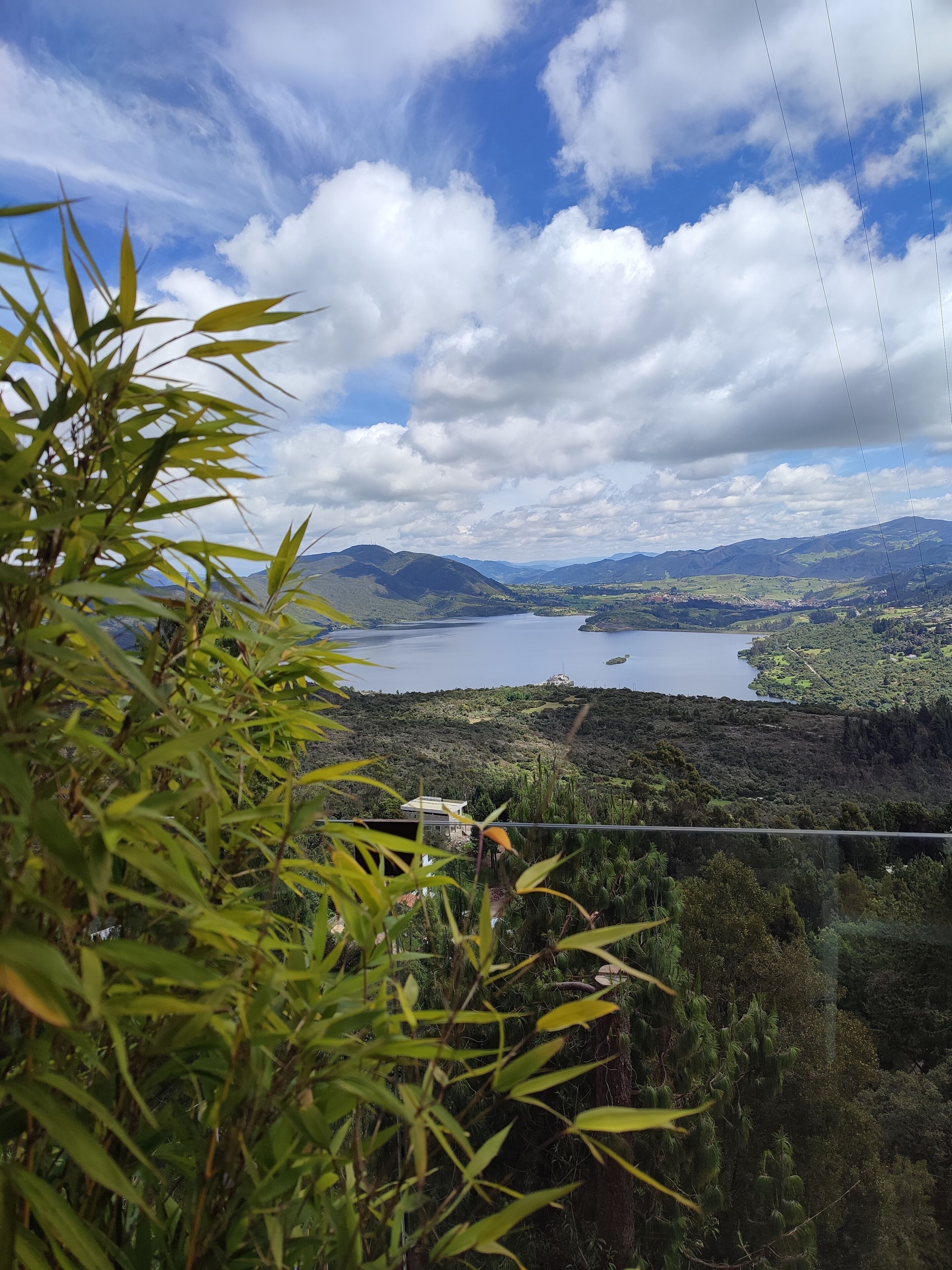 Une vue magnifique sur un lac entouré de montagnes et de verdure, sous un ciel dégagé.