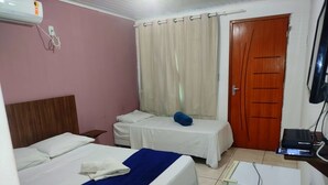 Habitación de hotel con dos camas, un cabecero de madera, un escritorio con computadora, un televisor y una ventana con cortinas.