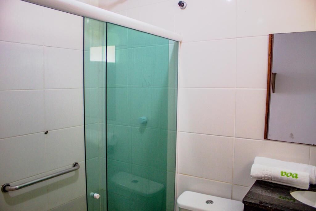 A bathroom with a glass shower enclosure, a white toilet, and a towel rack with a towel.