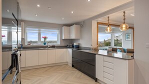 A modern kitchen with white cabinets, a black countertop, and a view of the outdoors.