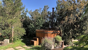 Un espace extérieur rustique agrémenté d’une barrique en bois, d’une cheminée et d’un sentier en pierre.