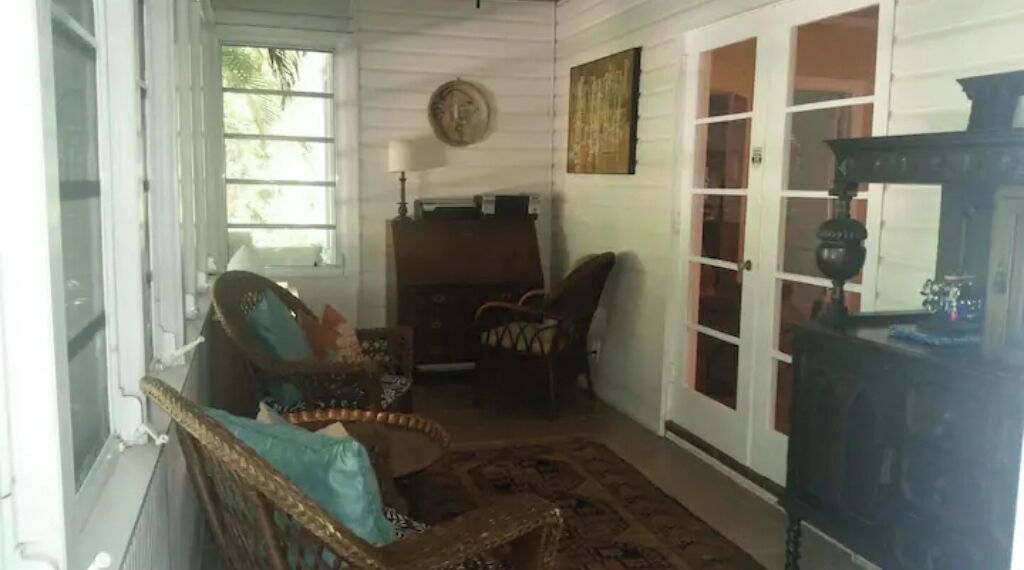 A room with wicker furniture, a wooden cabinet, and a patterned rug.