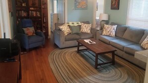 Un salon comprenant un canapé, des fauteuils, une table basse et une bibliothèque.