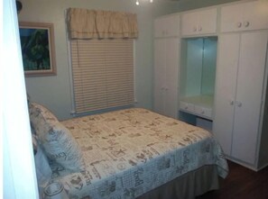 Ein Schlafzimmer mit Bett, Schrank und einem Fenster mit Jalousien.