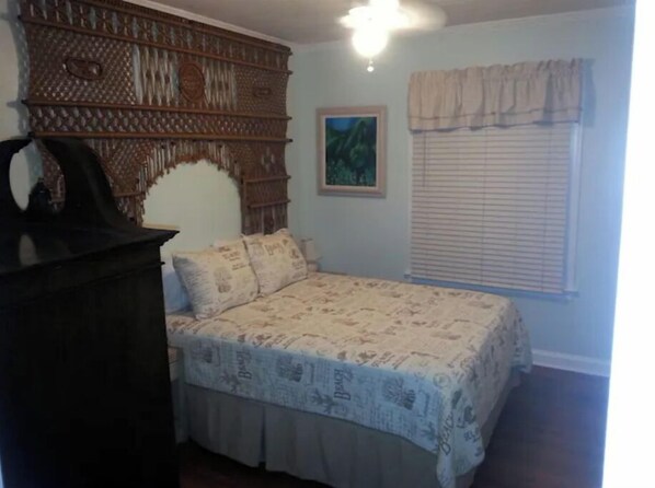 A bedroom with a bed, a dresser, a painting, and a window with blinds. - Loveday's Beach House 1 (Delray Beach)