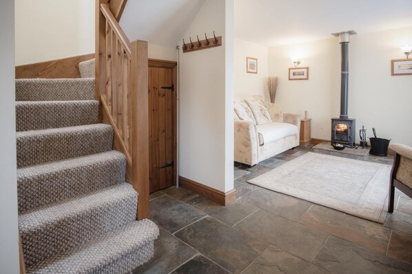 A staircase leading to a door, a sofa in a living area, and a wood-burning stove.