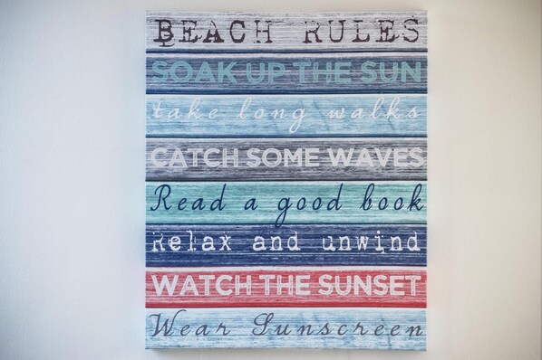 Un letrero vertical con varias frases relacionadas con la playa.