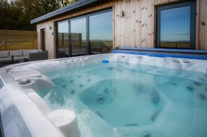 Ein Whirlpool mit Holzverkleidung und großen Fenstern.