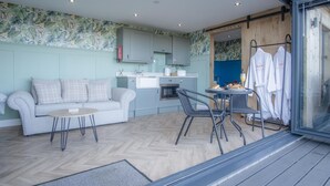 A modern, compact living space with a kitchenette, a dining area, and a seating area with a sofa and chairs.