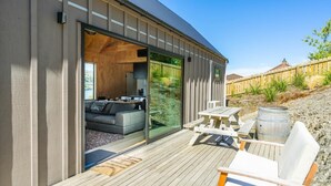 A modern house with a deck, a sofa, and a dining table. - Picture Perfect - Queenstown Holiday Home (Queenstown)