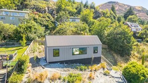 A modern house with a sloped roof, large windows, and a well-maintained garden. - Picture Perfect - Queenstown Holiday Home (Queenstown)