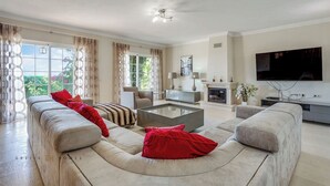 A spacious living room with a large sofa set, a coffee table, a fireplace, and a television. - Villa Diamond (Quarteira)
