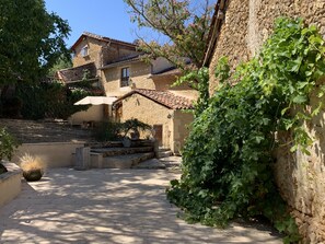 A rustic stone building with a tiled roof, a paved courtyard, and a large potted plant. - Unique Traditional French Farmhouse with private pool in rural Dordogne (Douzillac)