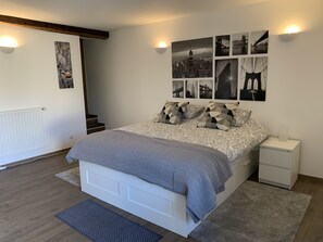 A bedroom with a bed, a nightstand, a radiator, and wall art. - Unique Traditional French Farmhouse with private pool in rural Dordogne (Douzillac)