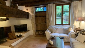 Ein gemütliches Wohnzimmer mit Fernseher, einer Couch, einem Couchtisch aus Holz und einem Korbstuhl.