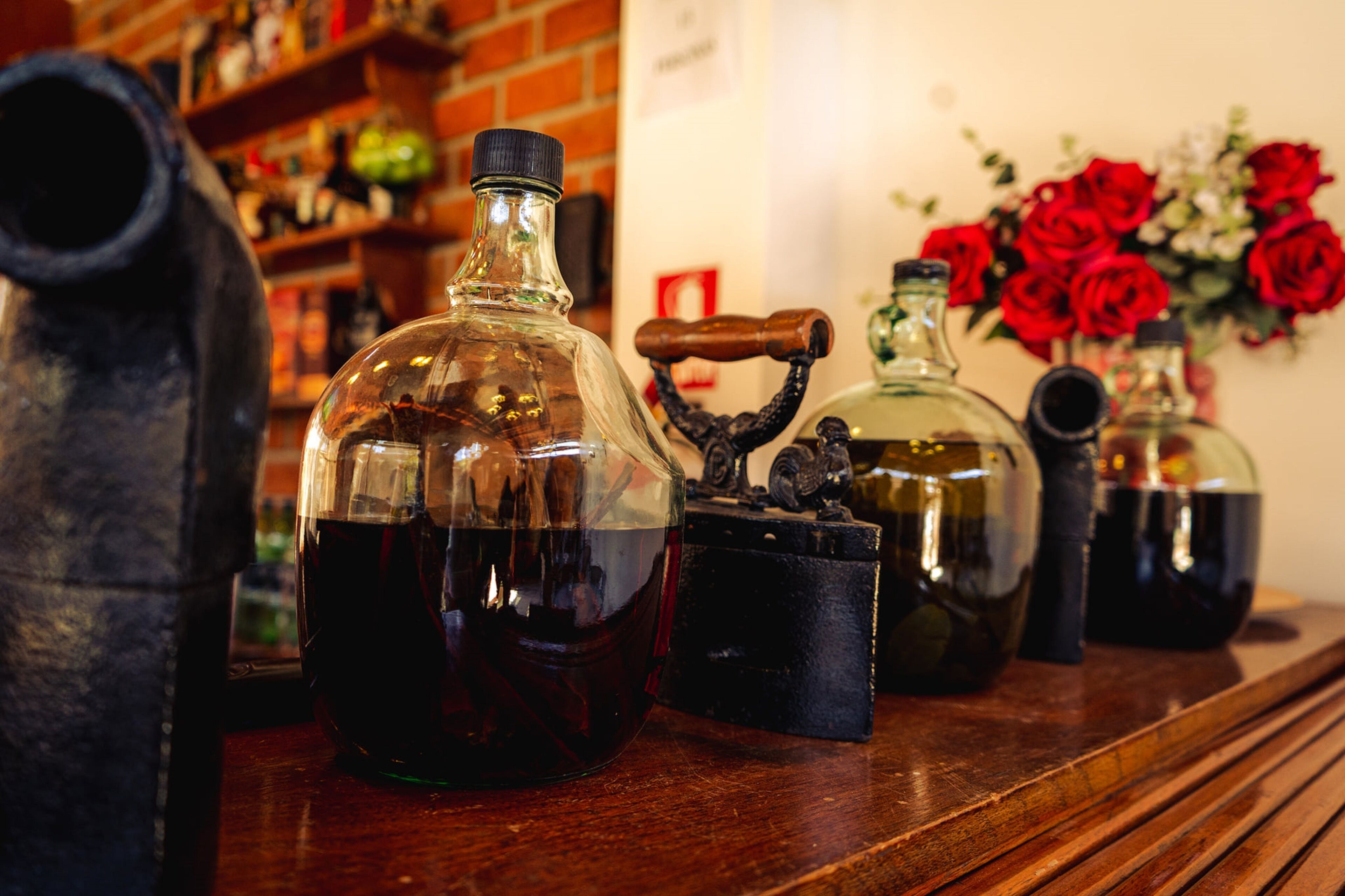 Una mesa de madera con varias botellas de vidrio y un recipiente metálico de estilo antiguo.