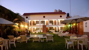 A hotel courtyard with a swimming pool, lounge chairs, and umbrellas. - Hotel Oro Viejo (Nazca)