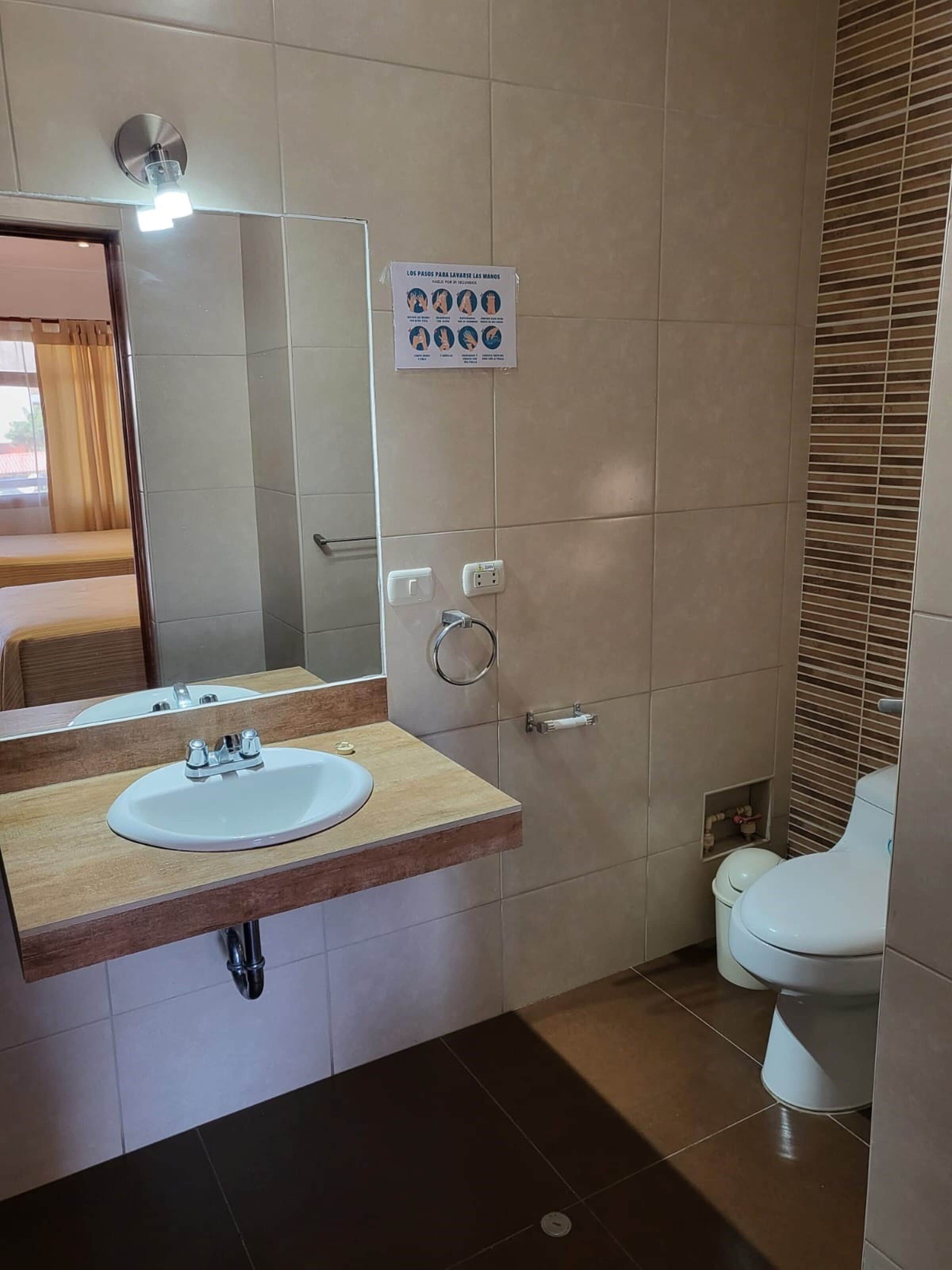 Un baño moderno con lavabo, espejo e inodoro.