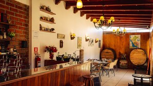 A rustic bar area with wooden shelves, a bar counter, stools, and a chandelier. - Hotel Oro Viejo (Nazca)
