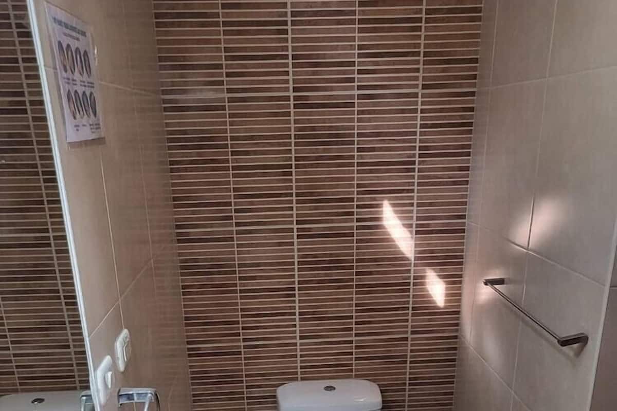 A bathroom with two toilets, a sink, and a mirror.