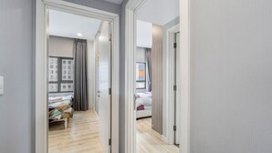 Un pasillo que conduce a un dormitorio con cama, ventana y puerta.
