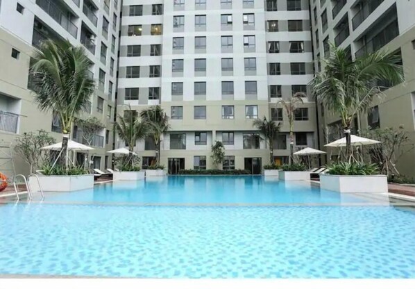 A swimming pool surrounded by a high-rise building with multiple balconies.