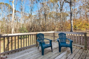 A wooden deck with two blue Adirondack chairs.