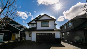 A two-story house with a garage, a driveway, and a clear sky with the sun shining. - What a view!  (Victoria)