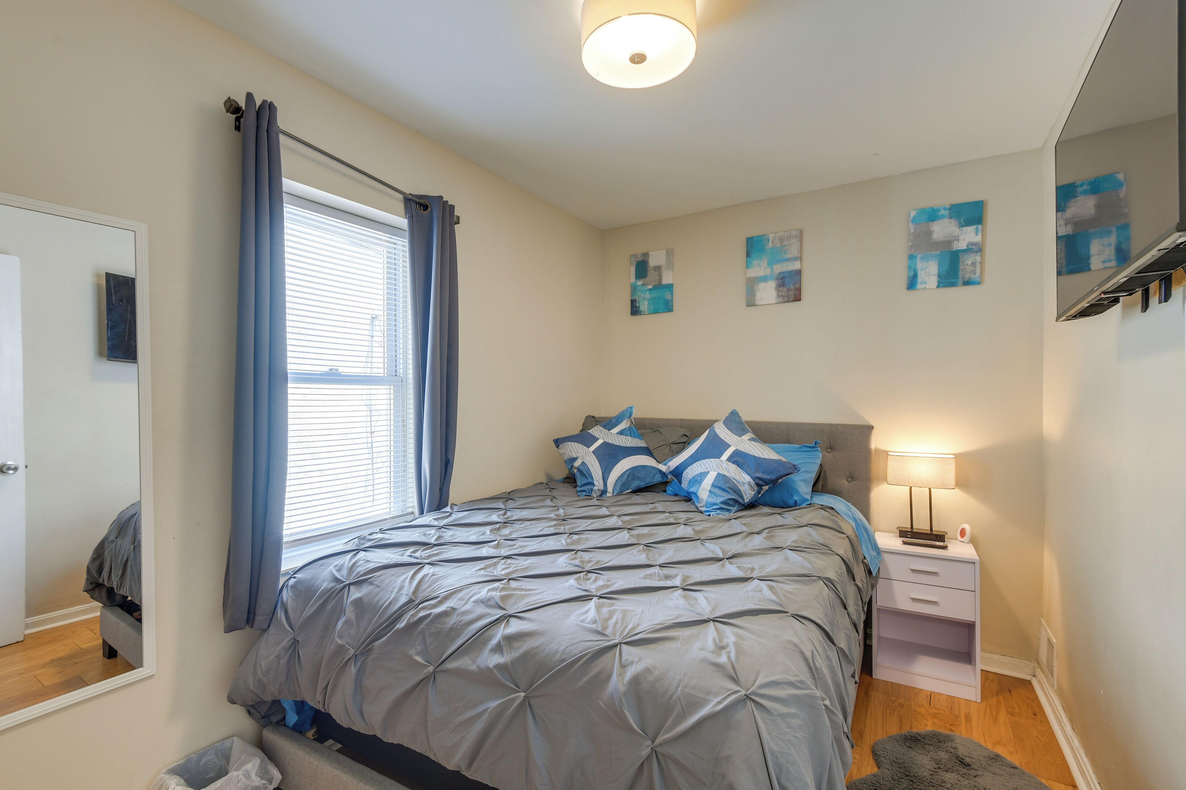 Un dormitorio con cama, mesita de noche, lámpara, ventana con cortinas y decoración en la pared.