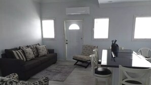 A modern living room with a sofa, armchair, and dining area with chairs and a table.