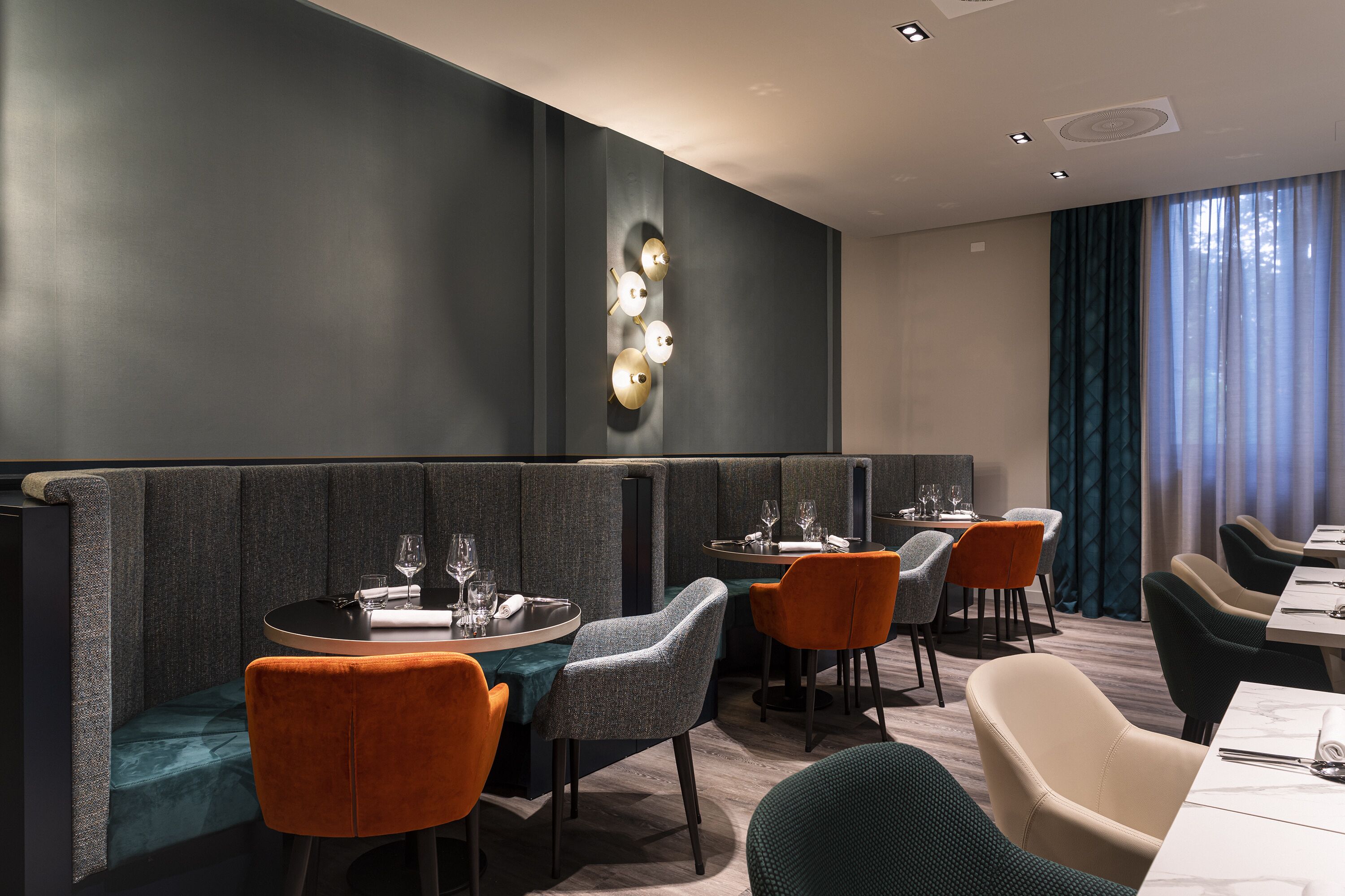 A modern restaurant with booth seating, a bar area, and a view of the outdoors.