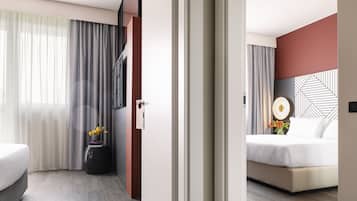 A hotel room with a bed, a nightstand, a wall-mounted TV, and a window with curtains.