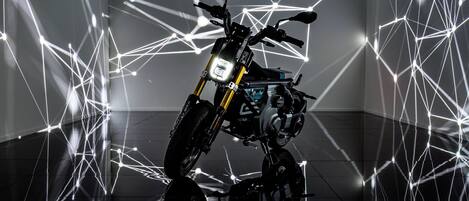 Une moto dans une pièce moderne dont le thème est basé sur des formes géométriques, avec un sol réfléchissant.