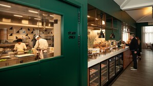 A kitchen area with a 'STAFF ONLY' sign, a buffet counter with various food items, and a counter with a wine cooler.