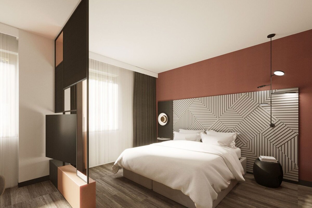 A modern bedroom with a bed, a TV, a side table, and a decorative wall panel.
