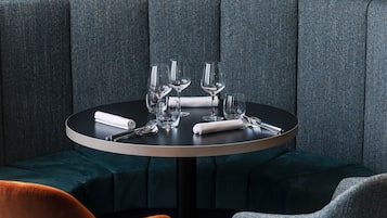 Una mesa redonda con tapa negra, rodeada de asientos tapizados en gris.