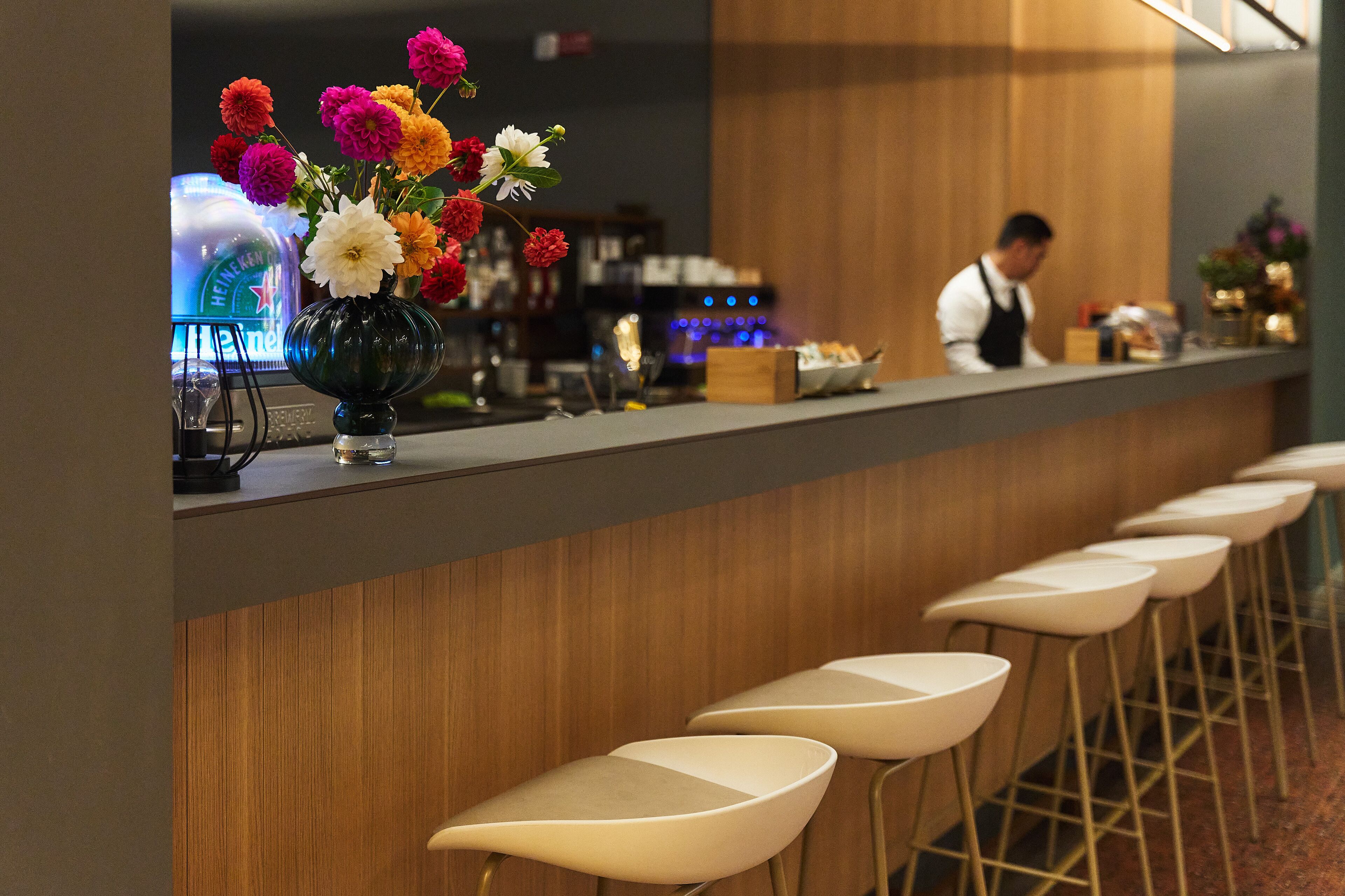 A bar area with a counter, stools, and a vase of flowers.
